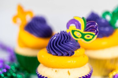 Mardi Gras vanilyalı kekler folyo kaplarda ve İtalyan tereyağlı kremayla süslenmiş..