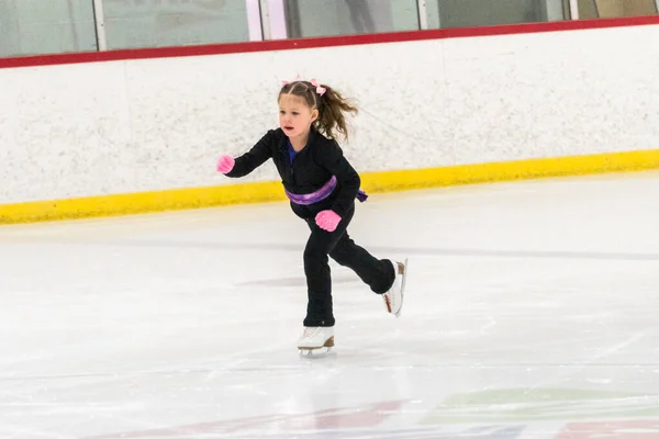 小さな女の子練習フィギュアスケートムーブオンザ屋内アイスリンク — ストック写真