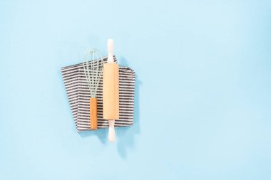 Düz yatıyordu. Mavi arka planda ahşap saplı yeni mavi silikon mutfak aletleri..