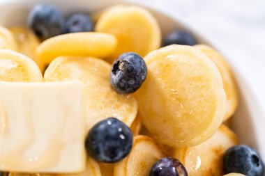 Taze yapılmış mini krep gevreği ve beyaz kasede taze yaban mersini..