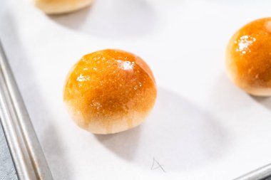 Parşömen kağıdıyla kaplanmış bir çarşafın üzerinde yumurta yıkama ile taze pişmiş yemek ruloları..