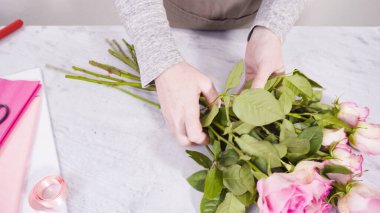 Adım adım. Çiçekçi pembe güllerden buket hazırlıyor..