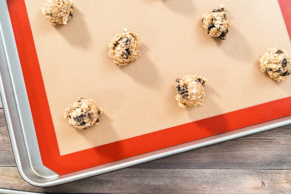 Scoops of cookie dough on a baking cheets to bake chewy oatmeal raisin cookies.