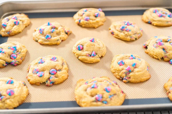 Freshly baked unicorn chocolate chip cookies on a baking sheet lined with a silicone mat.