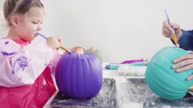 Küçük kız Cadılar Bayramı balkabağını ışıltıyla süslüyor..