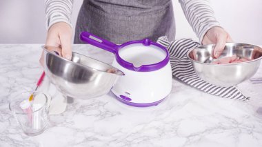 Adım adım. Çikolatalı şekerleri eritmek elektrikli bir şeker tenceresinde erir..