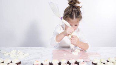 Adım adım. Küçük kız kesme tahtasına tereyağı kreması sürme alıştırması yapıyor.