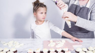 Adım adım. Küçük kız kesme tahtasına tereyağı kreması sürme alıştırması yapıyor.