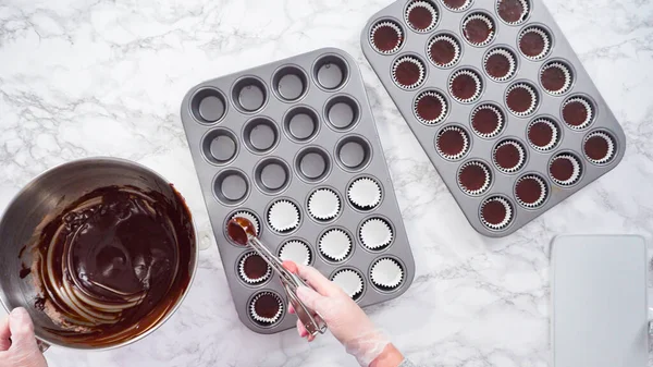 Düz yatıyordu. Adım adım. Mini çikolatalı kekler pişirmek için kek hamurunu mini kek kuyruklarına karıştırmak..