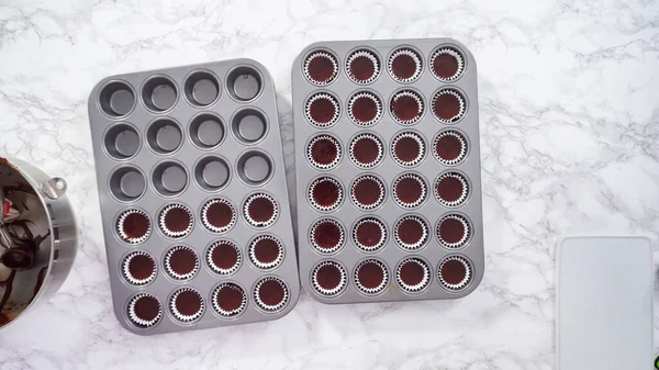 Düz yatıyordu. Adım adım. Mini çikolatalı kekler pişirmek için kek hamurunu mini kek kuyruklarına karıştırmak..