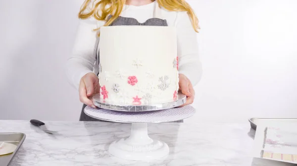 在高大的白色圆圆的蛋糕中加入雪片 作为最后的装饰 — 图库照片