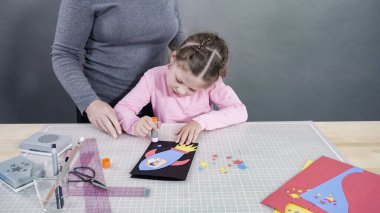 İnşaat kağıdından el yapımı Babalar Günü kartı yapan küçük bir kız..