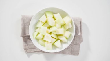 Adım adım. Düz yatıyordu. Beyaz kesme tahtasında kaygan altın çiğ taneli kavun.