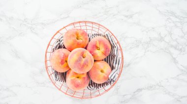 Düz yatıyordu. Adım adım. Mermer arka planda sepetteki organik şeftaliler..