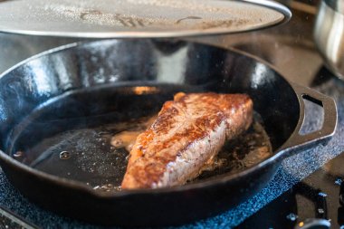 Elektrikli fırının üstünde kızgın demir tavayla New York bifteği kızartıyorum..