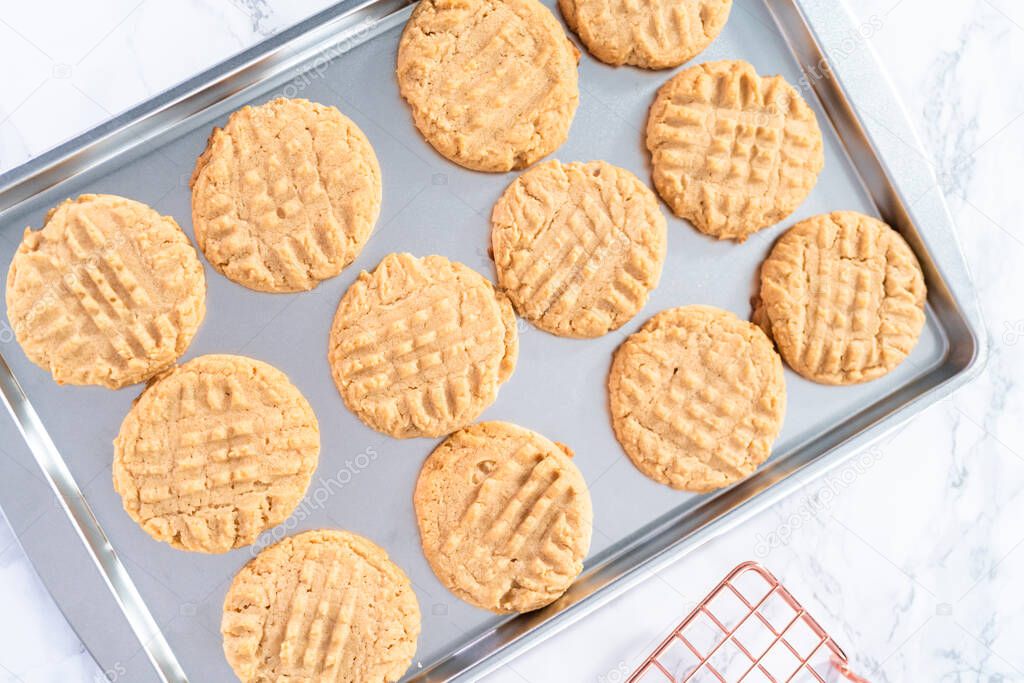 Freshly baked peanut butter cookies on a baking sheet.