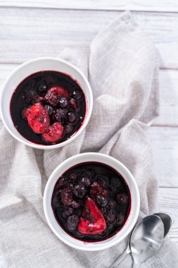 Ev yapımı böğürtlen kompostosu ahşap bir masada küçük beyaz kaselerde..
