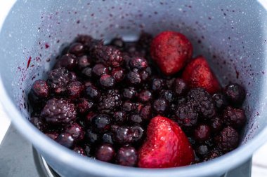 Donmuş böğürtlenlerin karışımını yapışmaz bir tencerede hazırlıyorum..