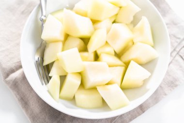 Beyaz bir kasede dilimlenmiş altın çiğ taneli kavun..