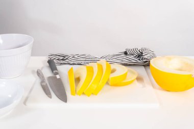 Beyaz kesme tahtasında kaygan altın çiğ taneli kavun.