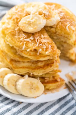 Dilimlenmiş muz ve kızarmış hindistancevizi ile süslenmiş taze hindistan cevizli krep yemek..