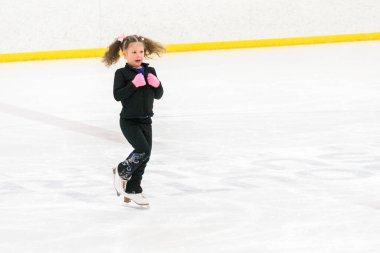 Küçük kız buz pistinde artistik patinaj yapıyor..