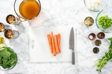 Düz yatıyordu. Beyaz bir kesme tahtasıyla organik havuç kesmek..