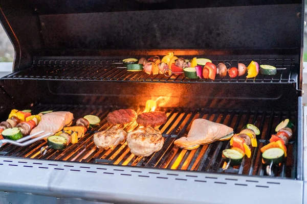 在室外烤架上烤大西洋鲑鱼 鸡胸肉 蔬菜串和素食汉堡 — 图库照片