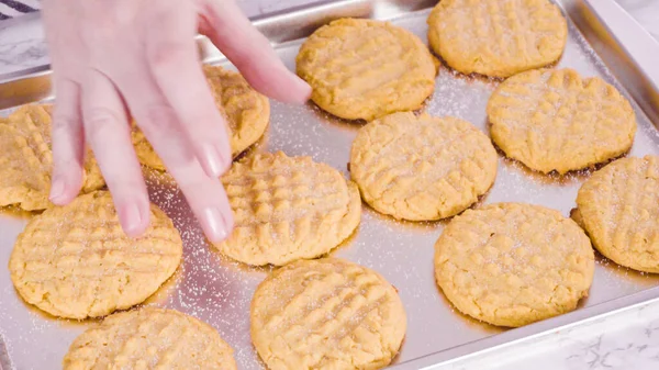 Step by step. Garnishing freshly baked peanut butter cookies with salt.