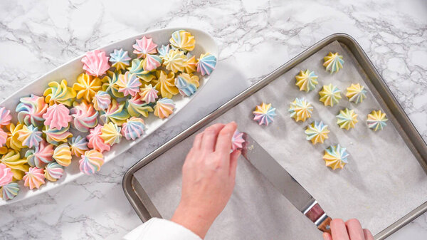 Step by step. Flat lay. Freshly baked unicorn meringue cookies on a baking sheet with a parchment paper.