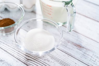 Ahşap bir masada yumurtalı ekmek hazırlamak için cam karıştırma kabındaki malzemeler..