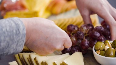 Büyük bir peynir tahtası için tahtanın üzerinde gurme peynir, kraker ve meyve düzenlemek.