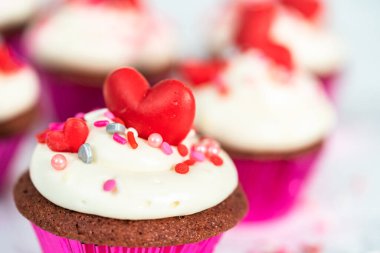 Krem peynirli kırmızı kadife kekler ve kalp ve öpücük şeklinde kırmızı çikolatalarla süslemeler..