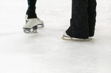 Artistik patinajda bir artistik patinajcı ve koçunun ayakları görülüyor..