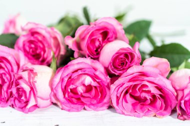 Boyanmış beyaz ahşap arka planı olan pembe güller..