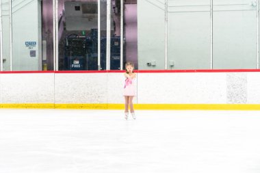 Küçük kız buz pateni pistinde artistik patinaj yapıyor..