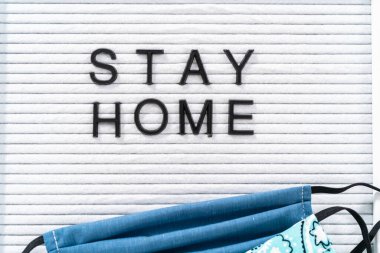 İleti panosunda ev yapımı yüz maskesi ile Ev Kal tabelası.