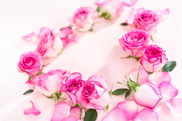 Форма сердца из розовых роз и лепестков роз на розовом фоне
.