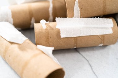 Gri arkaplanda boş tuvalet kağıdı ruloları kullanılıyor.