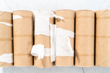 Gri arkaplanda boş tuvalet kağıdı ruloları kullanılıyor.