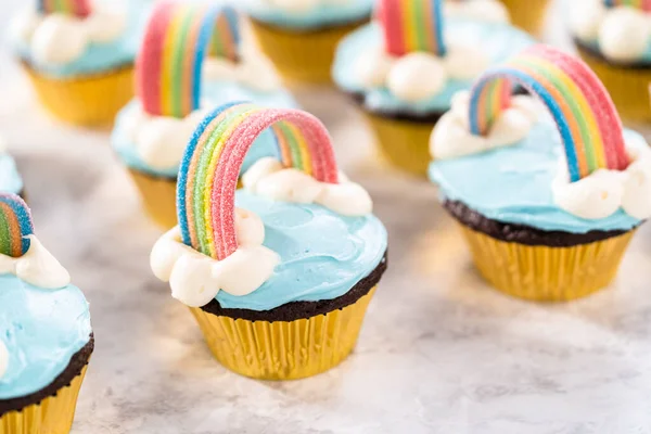 ブルーバタークリームのフリスティングとユニコーンのテーマの誕生日パーティーのための虹で飾られたチョコレートカップケーキ — ストック写真