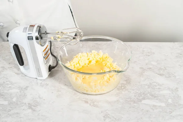 Mixing ingredients in a glass mixing bowl to bake funfettti bundt cake.