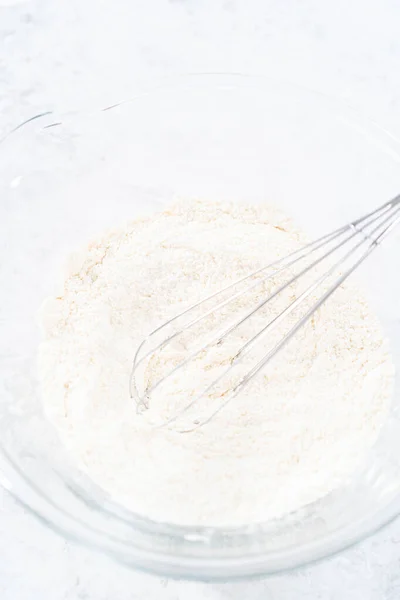 Mixing ingredients in a glass mixing bowl to bake funfettti bundt cake.