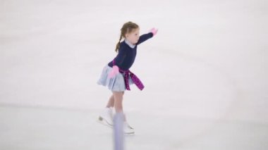 Küçük kız buz pateni pistinde artistik patinaj yapıyor..