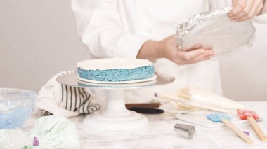 Yuvarlak üç katlı vanilyalı pasta yapmak için pasta katmanları yığılıyor.