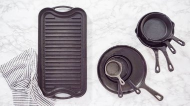 Düz yatıyordu. Mermer tezgahtaki dökme demir mutfak malzemelerinin çeşitliliği.