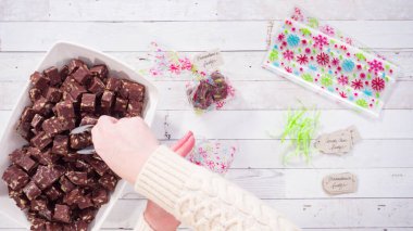 Düz yatıyordu. Adım adım. Ev yapımı macadamia şekerlemesi küçük hediye paketlerine konuyor..