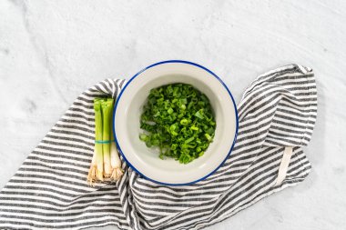 Düz yatıyordu. Metal bir kasede doğranmış organik yeşil soğan..