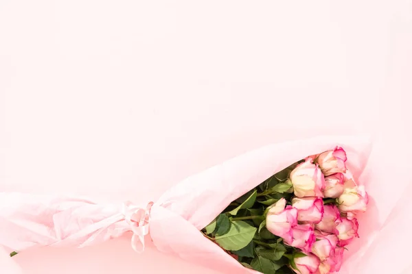 平置きだ ピンクの背景にピンクの紙に新鮮なピンクのバラのラッパーの花束 — ストック写真