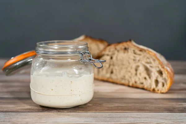 Feeding sourdough starter in a glass mason jar for baking artisan bread.